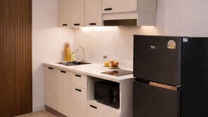 Una cocina moderna con armarios de colores claros, un refrigerador negro y un horno empotrado.