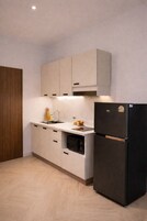 Una cocina moderna con armarios de colores claros, un refrigerador negro y un horno empotrado.