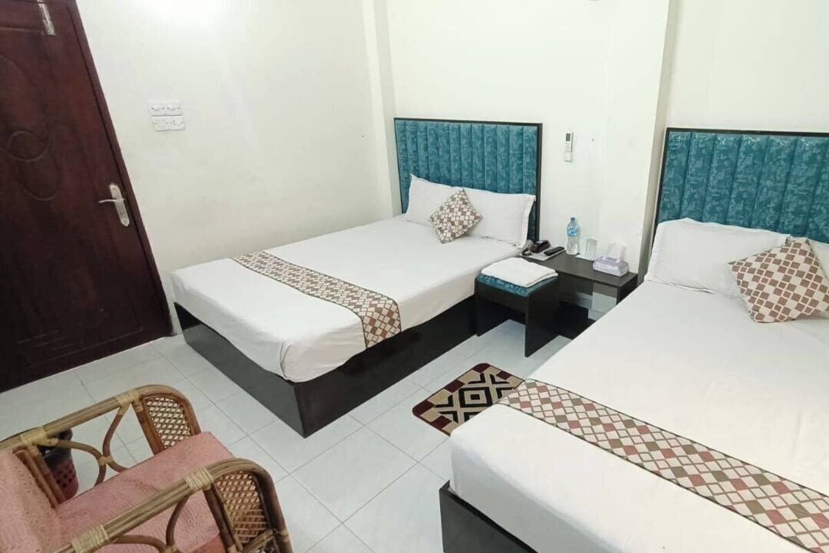 Une chambre d’hôtel avec deux lits, une petite table et une chaise.