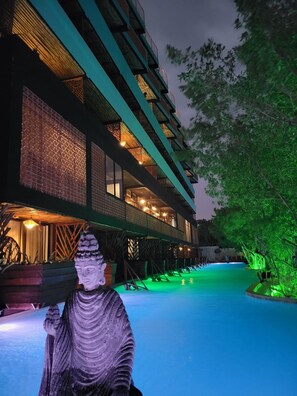 A building with multiple floors, a pool, and a statue. - Akuazul Resorts Adults Only Clothing Optional (Cancun)