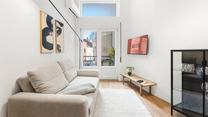 A modern living room with a sofa, a small table, a TV, and a glass cabinet. - GuestReady - Comfort in the heart of Porto City (Porto)