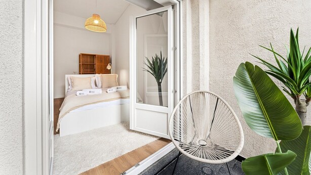 A bedroom with a bed, a bedside table, a lamp, and a window. - GuestReady - Comfort in the heart of Porto City (Porto)