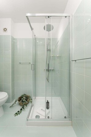 A glass-enclosed shower stall with a handheld showerhead, a handheld showerhead, and a wall-mounted faucet. - GuestReady - Comfort in the heart of Porto City (Porto)