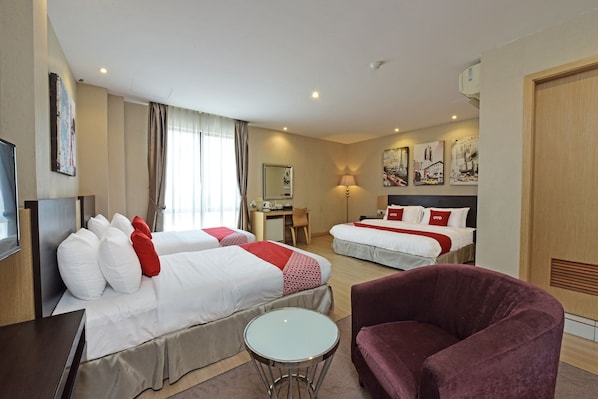 A hotel room with two beds, a desk, a chair, a round table, and a TV.