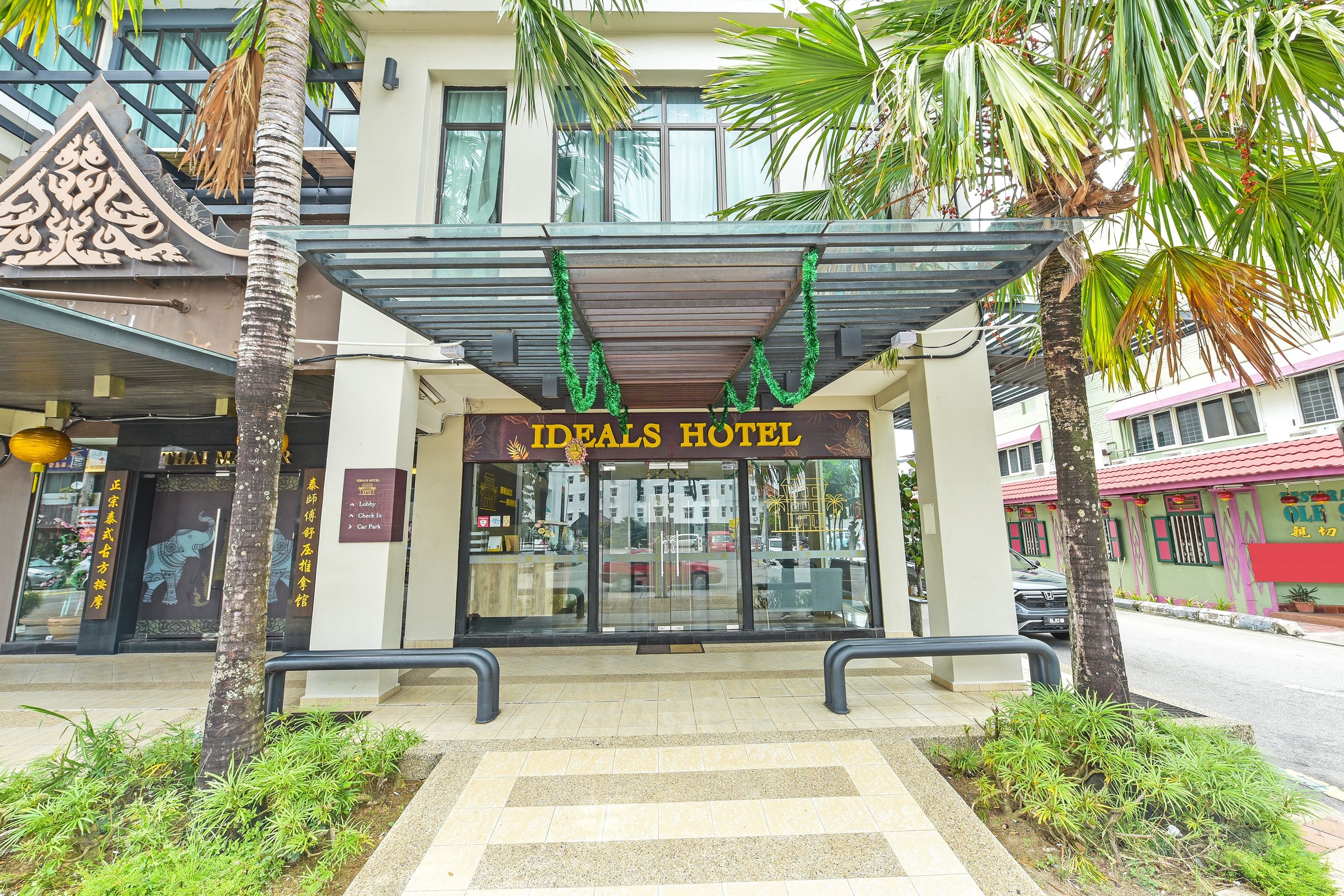 L’entrée de l’hôtel Ideals, avec une allée couverte et des palmiers.