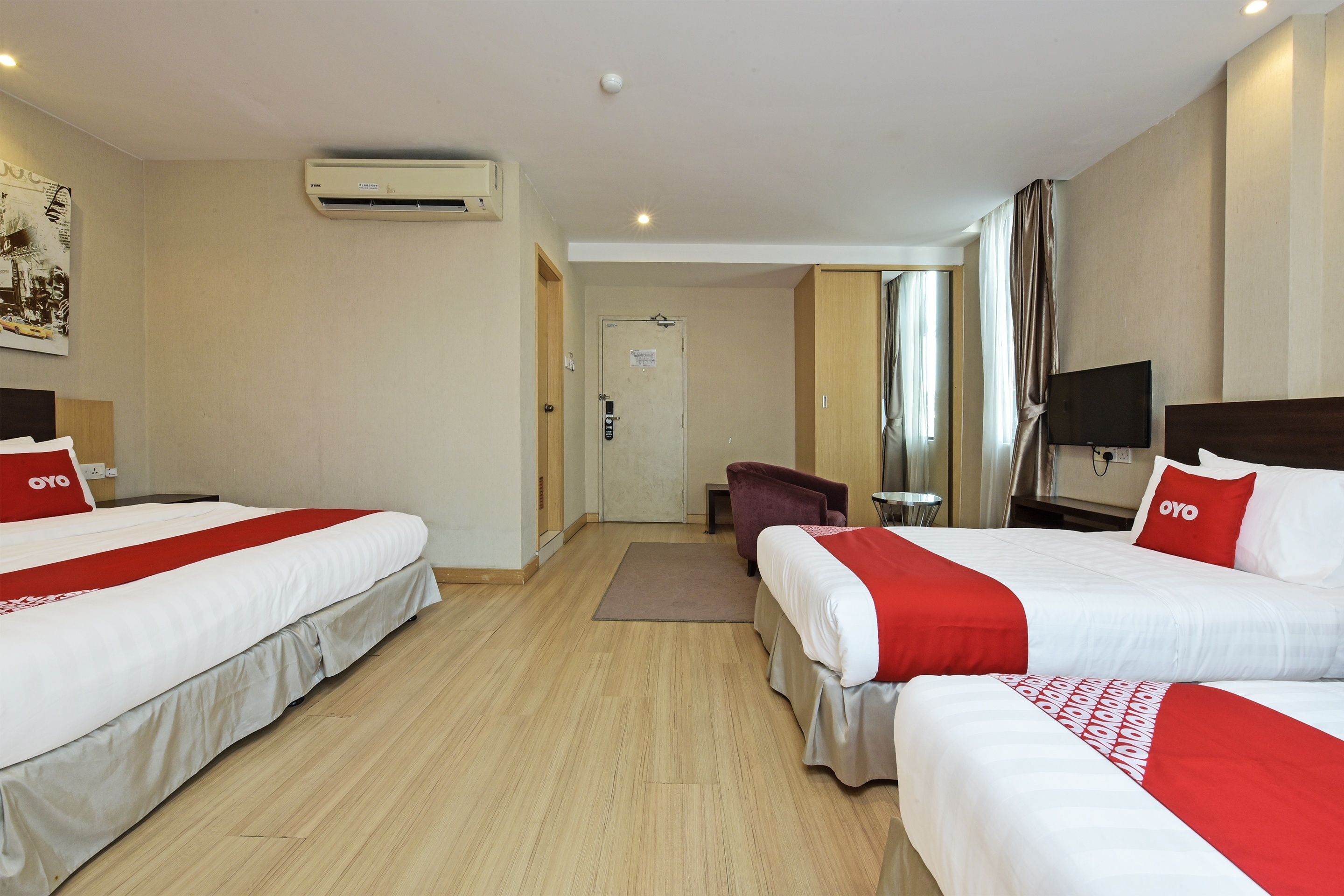 Una habitación de hotel con dos camas, televisión, aire acondicionado y una puerta que da a un baño.