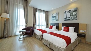 A hotel room with two beds, a chair, a lamp, and artwork on the wall. - Townhouse Oak Melaka Near Dataran Pahlawan (Malacca City)