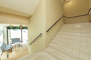 Eine Treppe mit beigen Wänden und weißen Fliesen, die zu einer Sitzecke mit einer Bank und einem kleinen Tisch führt.
