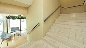 A staircase with beige walls and white tiles, leading to a seating area with a bench and a small table. - Townhouse Oak Melaka Near Dataran Pahlawan (Malacca City)