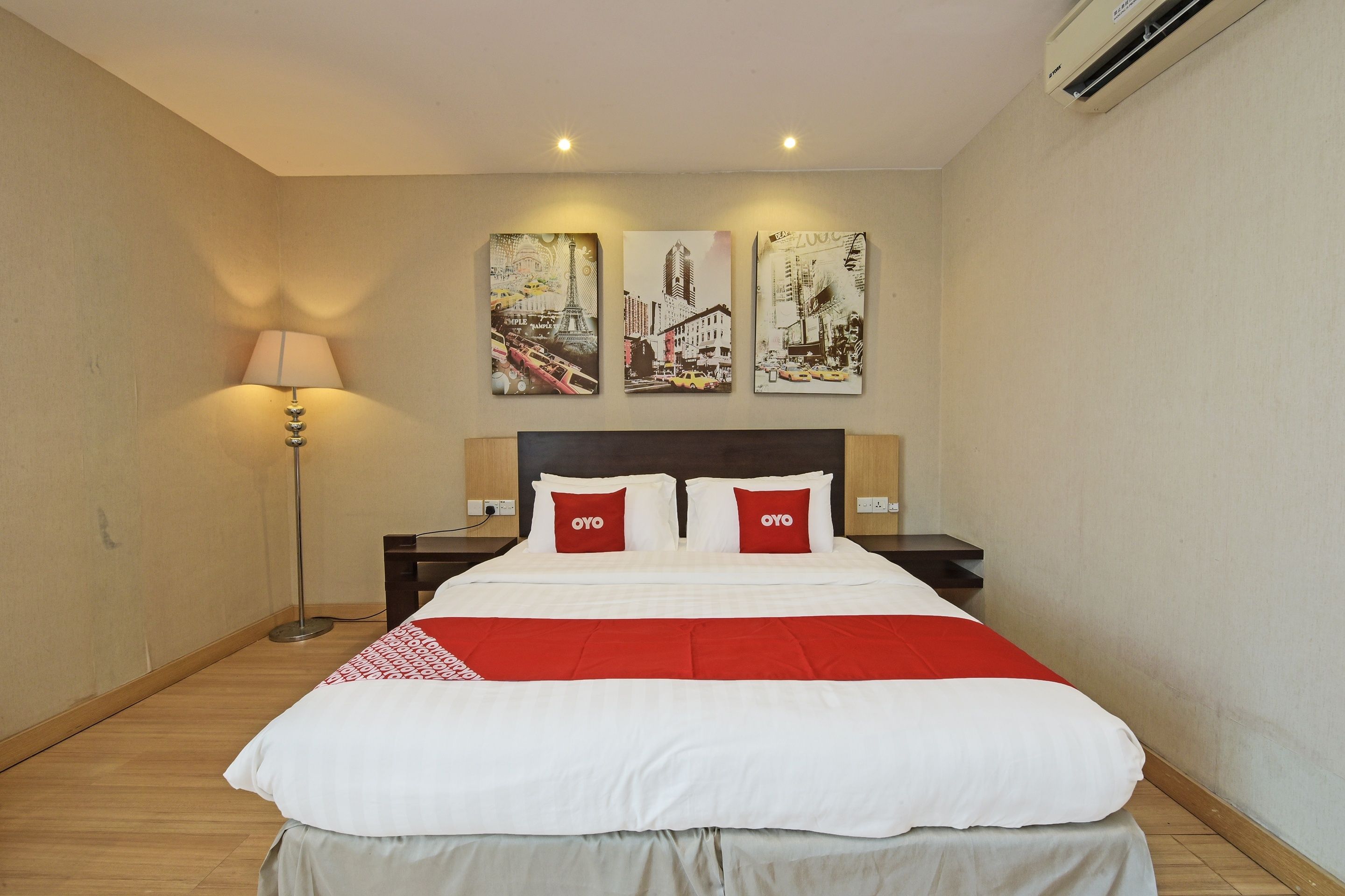 Una habitación de hotel con una cama, una mesita de noche, una lámpara y tres cuadros en la pared.