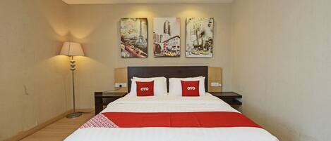 A hotel room with a bed, a nightstand, a lamp, and three wall art pieces.