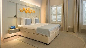 Un dormitorio moderno con una cama grande, una mesita de noche con un reloj y una lámpara fijada en la pared.