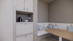 Una kitchenette moderna con cafetera integrada, una mesa pequeña y una zona de estar con sofá y cojines.
