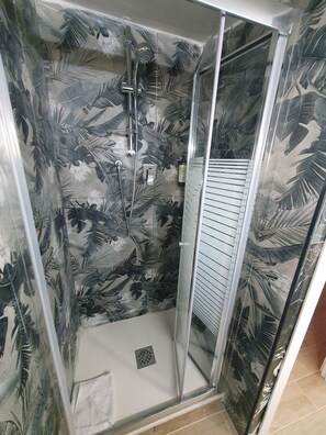 A shower with a glass door and a leaf-patterned wall. - Albergo Flaminia Rooms (Rome)