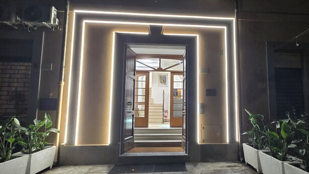 A hotel entrance with a modern design, featuring a neon-lit frame and a staircase leading to the interior. - Albergo Flaminia Rooms (Rome)