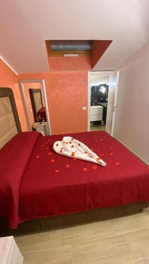A bedroom with a red bedspread, a white blanket with red accents, and a skylight above the bed. - Albergo Flaminia Rooms (Rome)