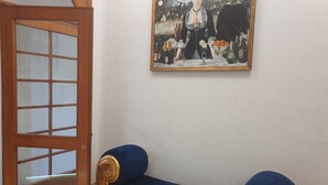 A room with a blue sofa, a wooden door with glass panels, and a painting on the wall. - Albergo Flaminia Rooms (Rome)