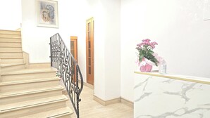 A staircase with a black railing, a wooden door, and a marble countertop with a vase of flowers. - Albergo Flaminia Rooms (Rome)