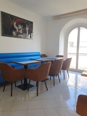 Interior de restaurante con asientos en una cabina azul, mesas y sillas de madera.