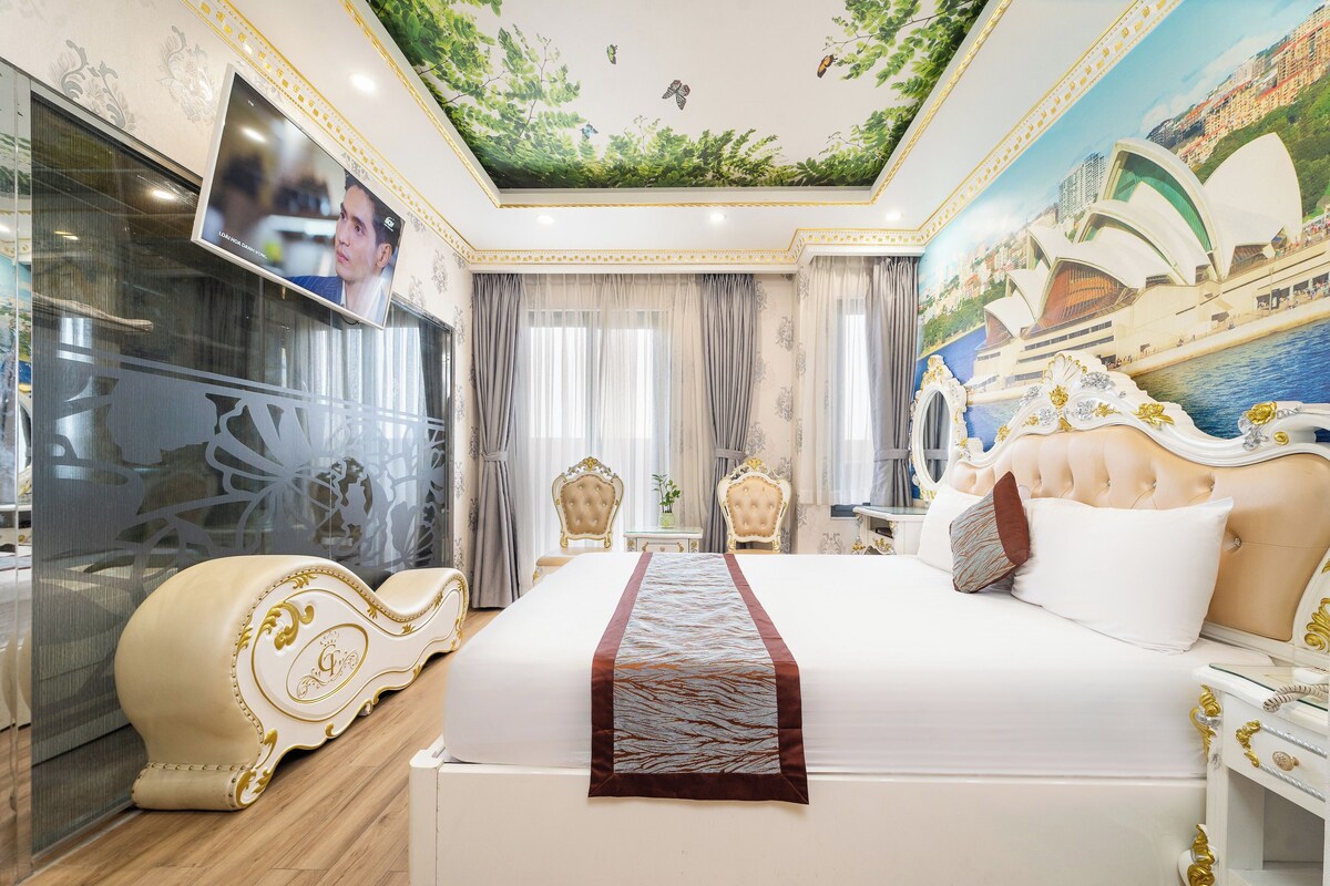 A luxurious hotel room with a large bed, ornate furniture, a ceiling mural, and a view of the Sydney Opera House.