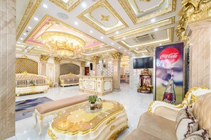Un hall d’entrée luxueux, agrémenté de motifs dorés ouvragés, d’un imposant lustre et d’une publicité pour Coca-Cola.