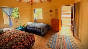 Une chambre avec deux lits, une commode en bois et une fenêtre avec des rideaux.