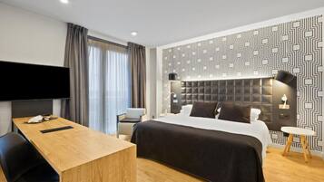 Habitación de hotel moderna con una cama grande, un escritorio, un televisor de pantalla plana y un papel tapiz estampado.
