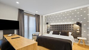 A modern hotel room with a large bed, a desk, a flat-screen TV, and a patterned wall. - B&b Hotel Tarragona Valls  (Alio)