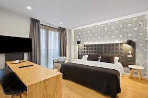 A modern hotel room with a large bed, a desk, a flat-screen TV, and a patterned wall. - B&b Hotel Tarragona Valls  (Alio)