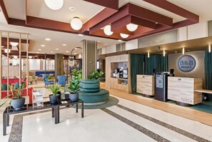 A hotel reception area with a reception desk, seating area, and a counter with a B&B logo. - B&b Hotel Tarragona Valls  (Alio)