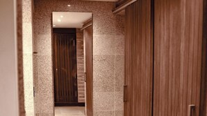 Un couloir avec un mur recouvert de miroirs, une armoire en bois et un sol carrelé.