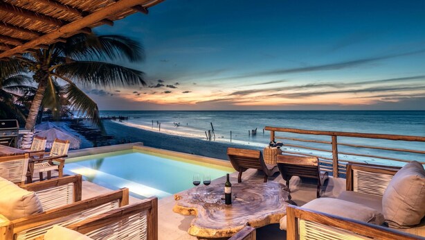 A beachside lounge with a pool, wooden furniture, and a view of the ocean at sunset. - Hotel Boutique Casa Muuch Holbox - Solo Adultos (Isla Holbox)