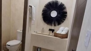 A small bathroom with a toilet, sink, and a round mirror on the wall. - Hotel Boutique Casa Muuch Holbox - Solo Adultos (Isla Holbox)