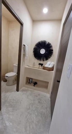 A small bathroom with a toilet, sink, and a round mirror on the wall. - Hotel Boutique Casa Muuch Holbox - Solo Adultos (Isla Holbox)