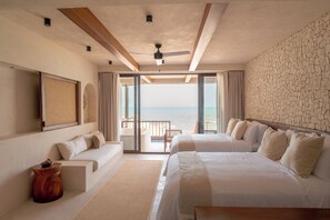 Ein Hotelzimmer mit einem großen Bett, einem kleineren Bett, einer Couch und Meerblick.