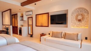 Une chambre d’hôtel moderne dotée d’un grand lit, d’un canapé, d’une télévision et d’un mur décoré avec des pierres apparentes.