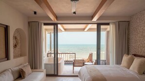 A bedroom with a large bed, a sofa, and a view of the sea through a sliding glass door. - Hotel Boutique Casa Muuch Holbox - Solo Adultos (Isla Holbox)