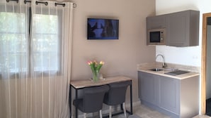 A compact kitchen with a built-in microwave, a sink, and a small dining area with two chairs and a table. - Etoile De Saint Paul (Saint-Paul-de-Vence)