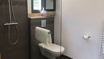 A bathroom with a shower, toilet, and a towel rack.
