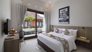 A modern hotel room with a large bed, a desk, a chair, and a TV.
