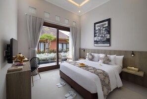A modern hotel room with a large bed, a desk, a chair, and a TV. - Tapa Agung View Hotel & Restaurant (Rendang)