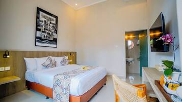 A modern hotel room with a large bed, bedside tables, a mounted TV, and a bathroom visible through an open door.