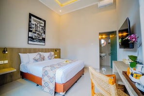 A modern hotel room with a large bed, bedside tables, a mounted TV, and a bathroom visible through an open door. - Tapa Agung View Hotel & Restaurant (Rendang)