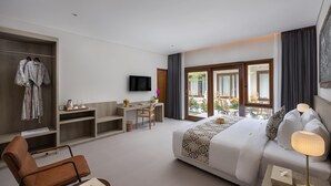 A hotel room with a bed, a desk, a chair, a TV, and a balcony with a view.