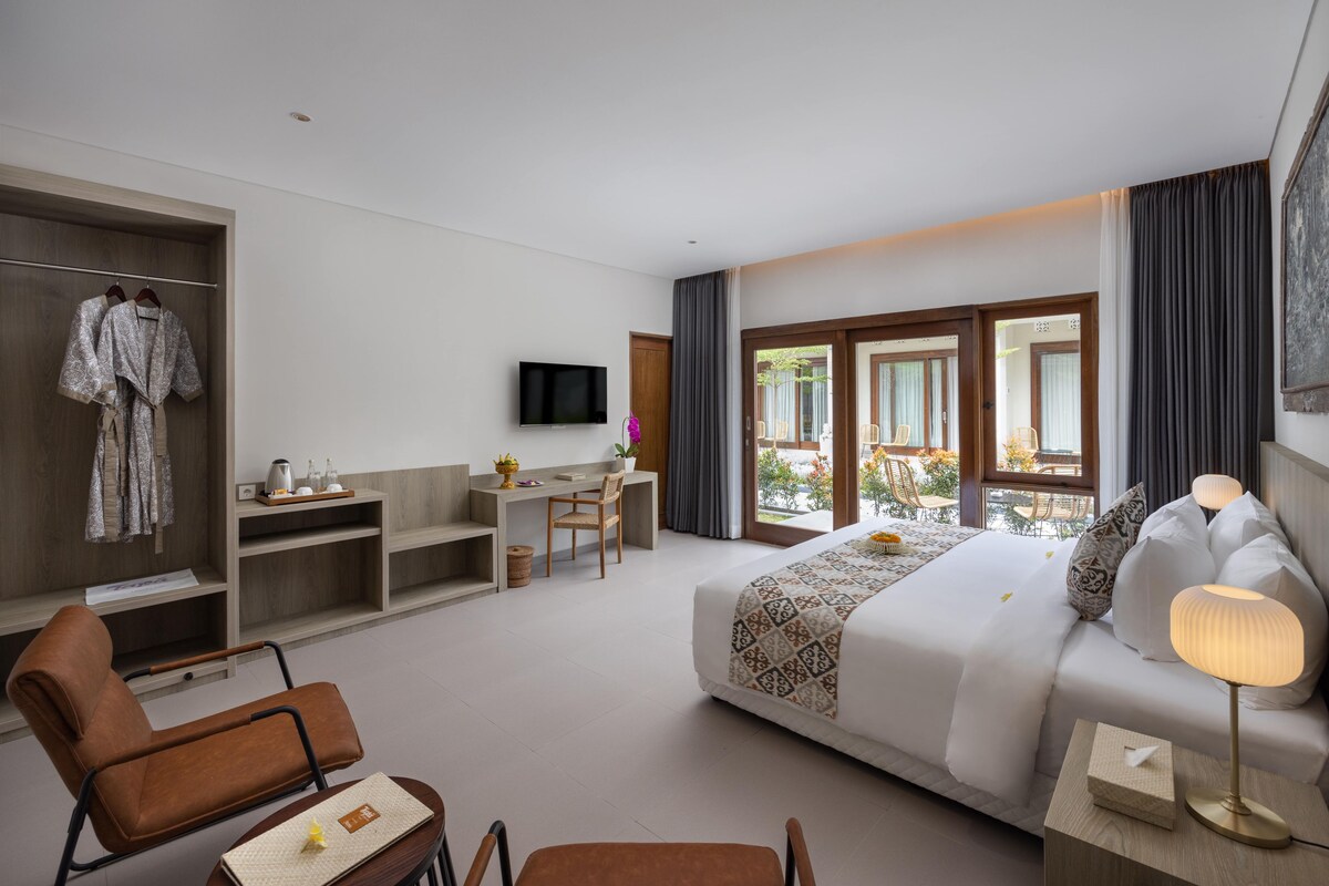 A hotel room with a bed, a desk, a chair, a TV, and a balcony with a view.