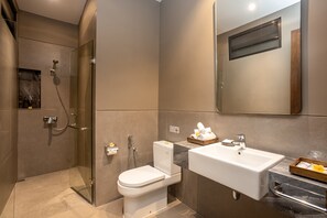 Ein modernes Badezimmer mit einer gläsernen Duschkabine, einer weißen Toilette, einem Waschbecken mit Marmorplatte und einem Spiegel darüber.