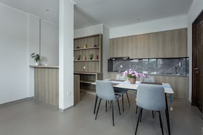 A modern kitchen with wooden cabinets, a marble countertop, and a dining area with two chairs and a table. - Tapa Agung View Hotel & Restaurant (Rendang)