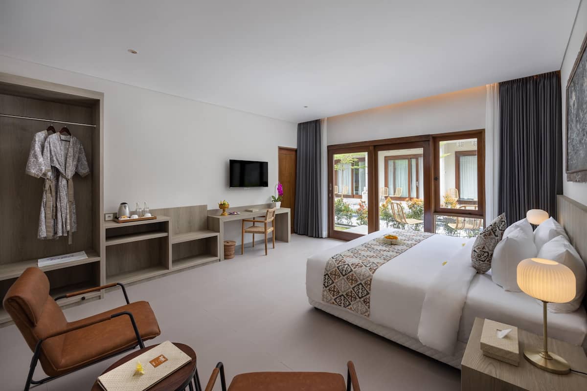 A hotel room with a bed, a desk, a chair, a TV, and a balcony with a view.