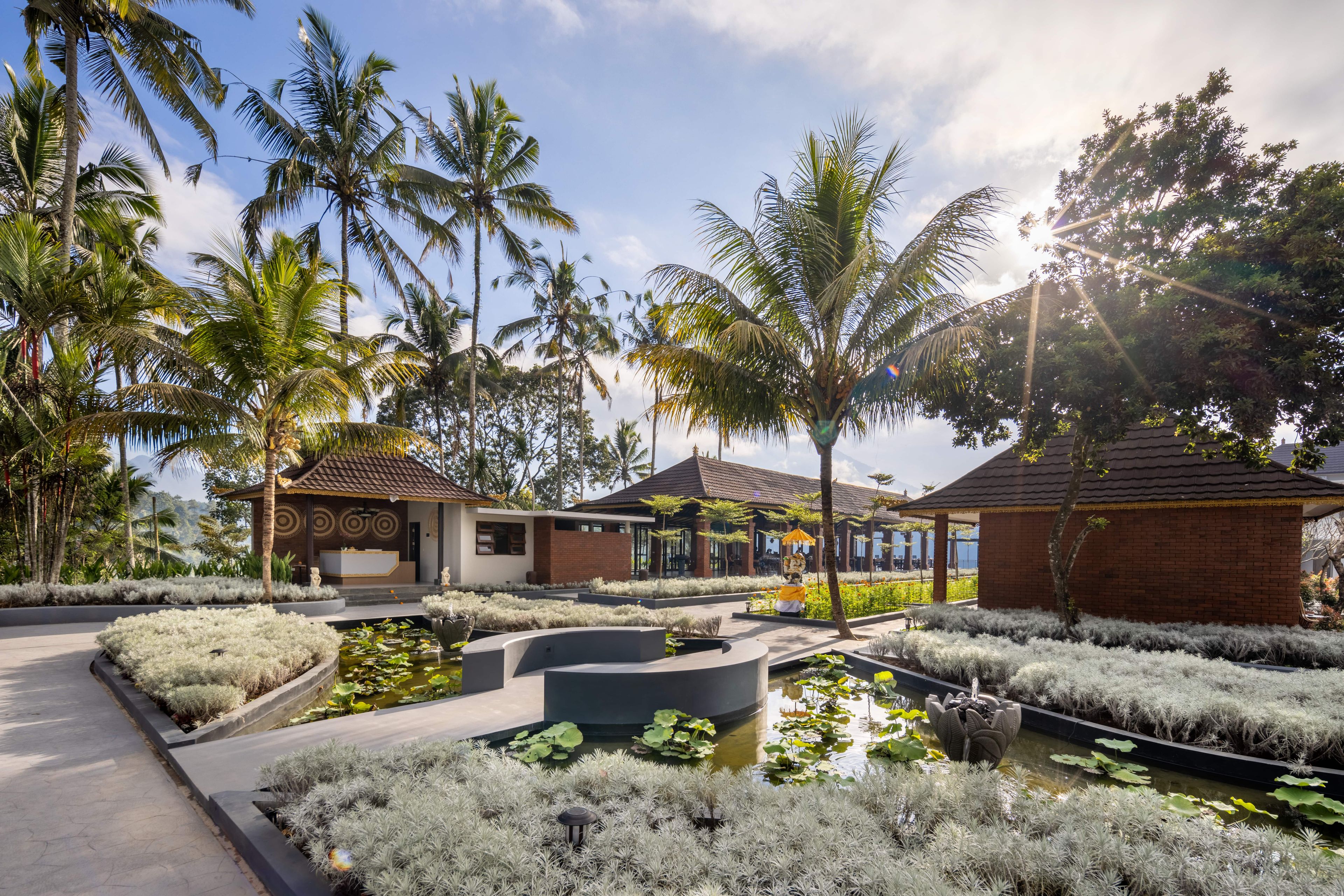 Un resort con fuente central, palmeras y edificios de estilo tradicional.