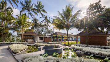 Un resort con fuente central, palmeras y edificios de estilo tradicional.